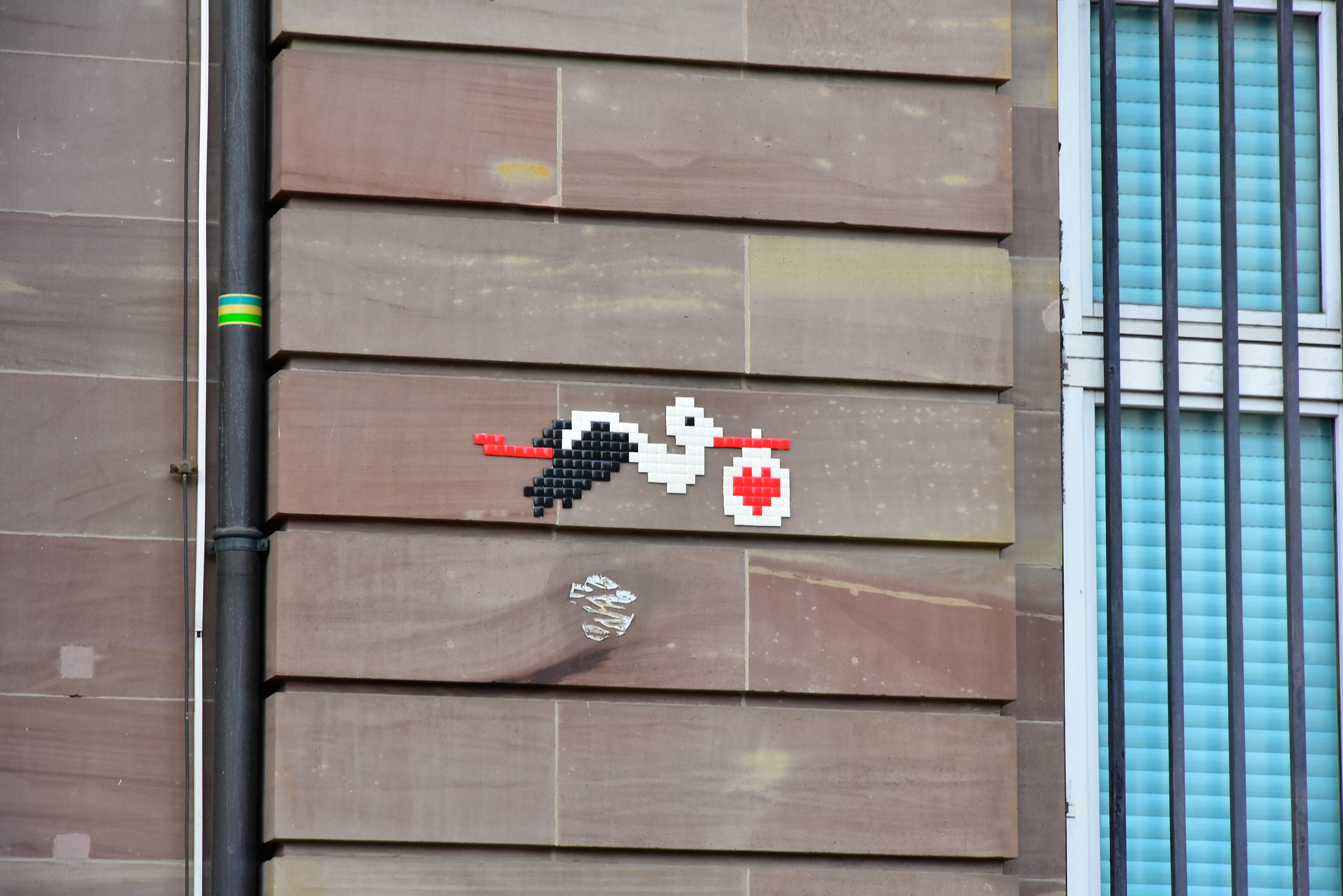 A stork carrying a sack with a hearth on it, mozaic on wall